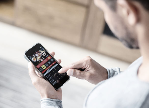 a man in a gray shirt with his back to the image, fiddling with his cell phone on a sports betting website