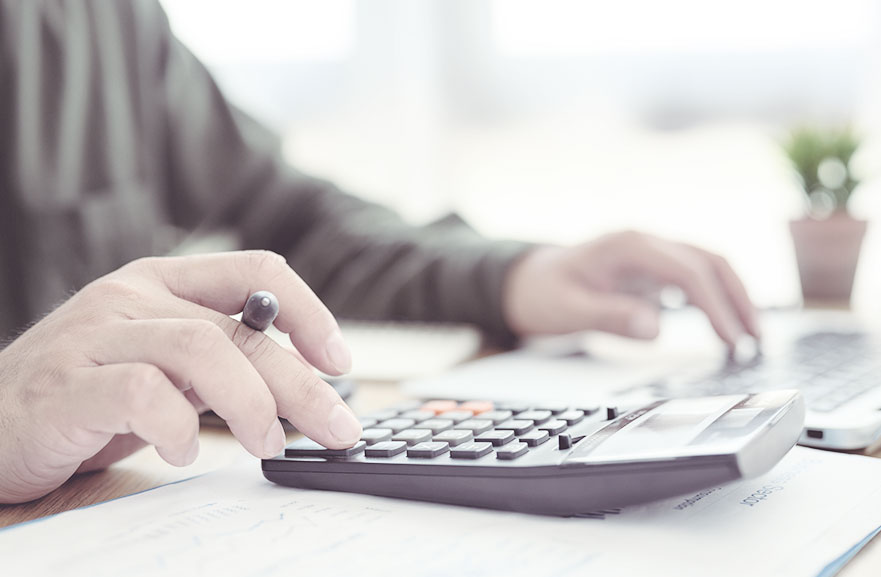 Pessoa utilizando calculadora preta com teclas em preto e vermelho